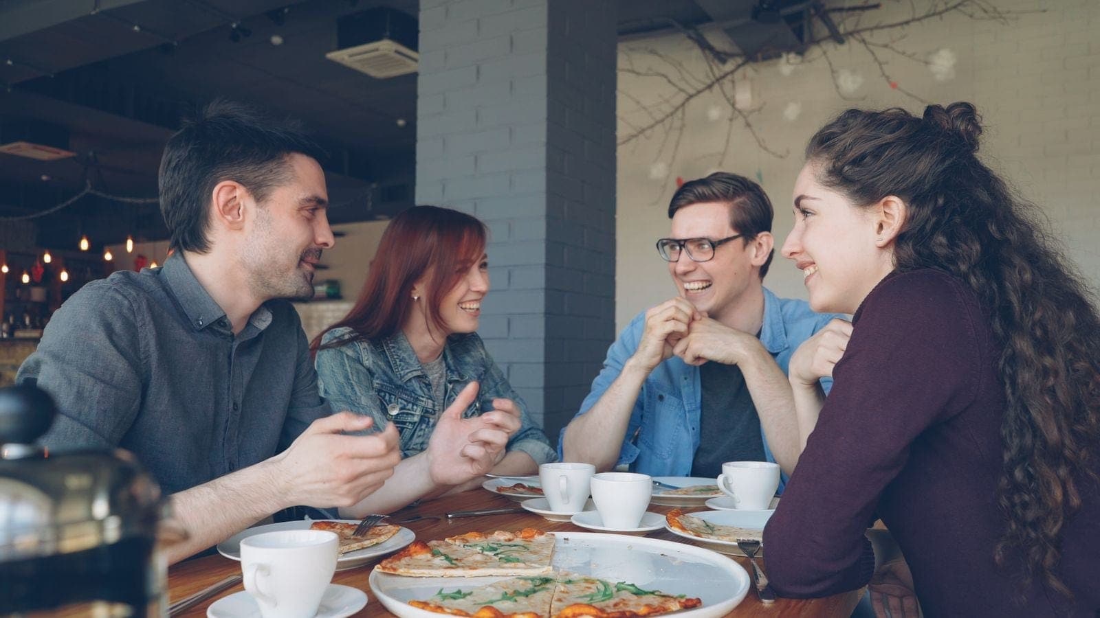 Young Friends Enjoying Pizza and Coffee in Cafe