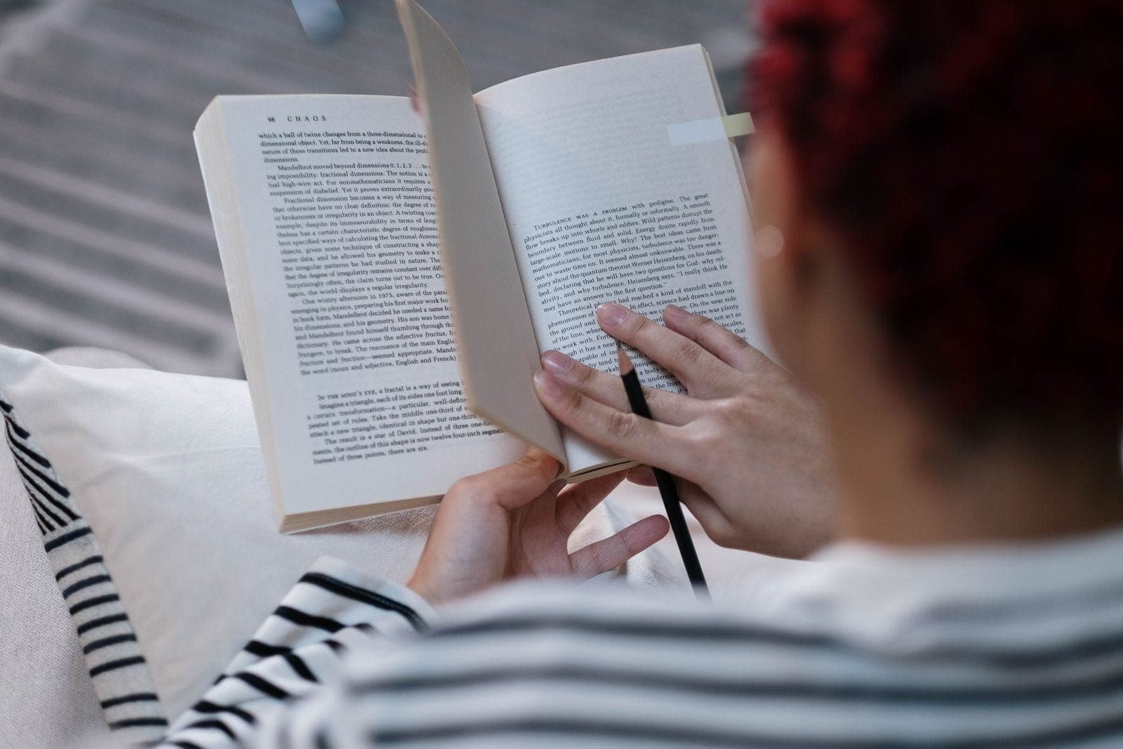 A reader holding an open paperback book