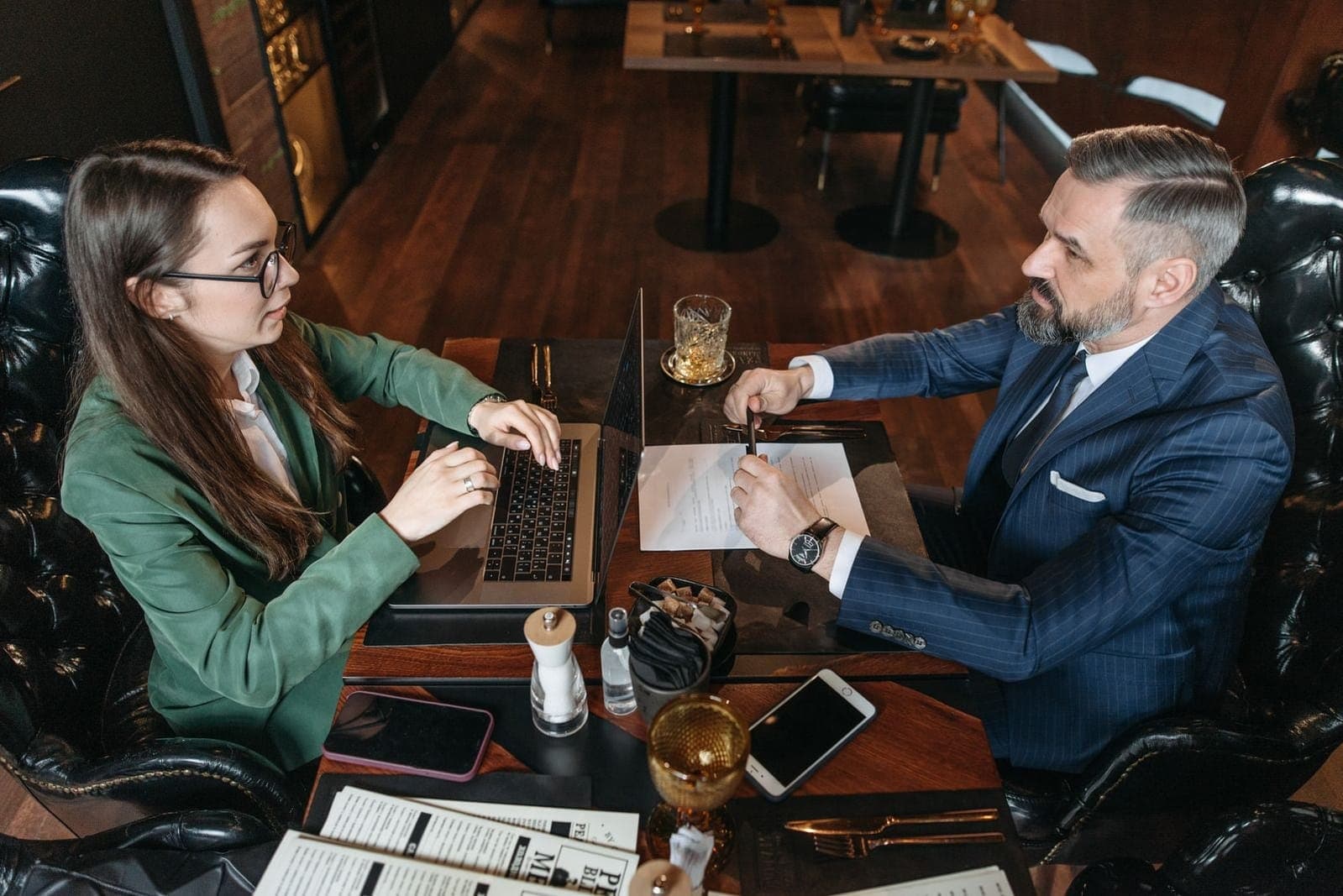 Two professionals discussing notes beside a laptop