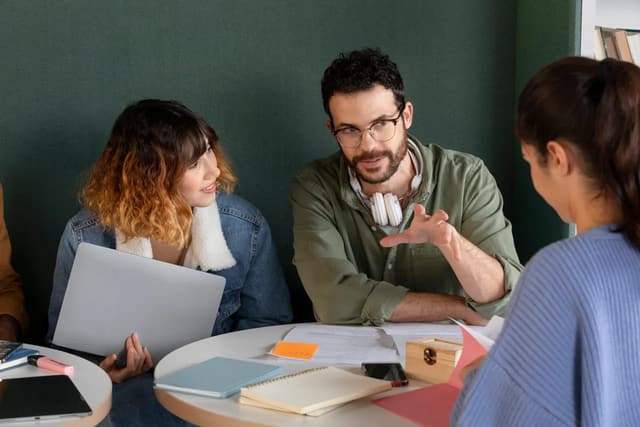 Colleagues discussing ideas around laptops at a meeting table