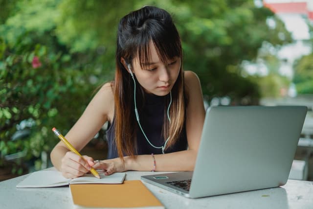 Focused woman with laptop and notebook