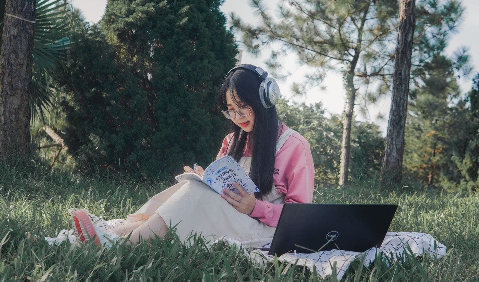A Woman Wearing Headphones Writing on a Notebook