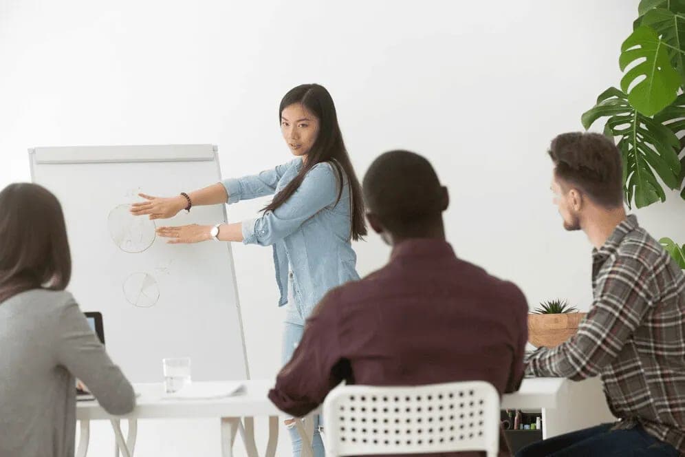 A woman explaining a topic to a small seated group in a workshop