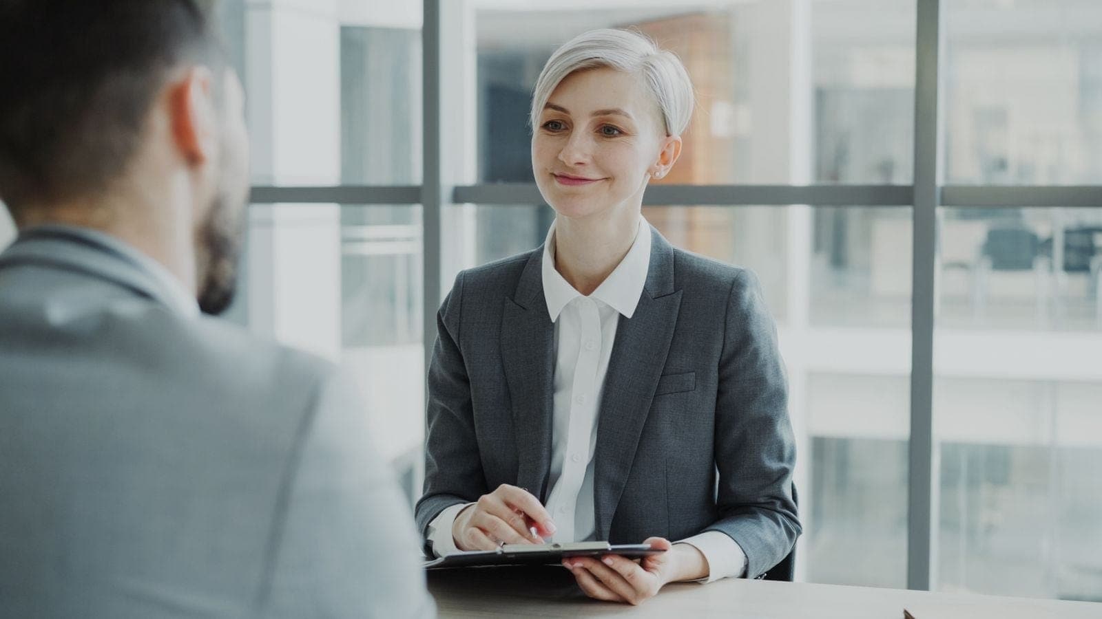 A professional holding a tablet during a face-to-face office conversation