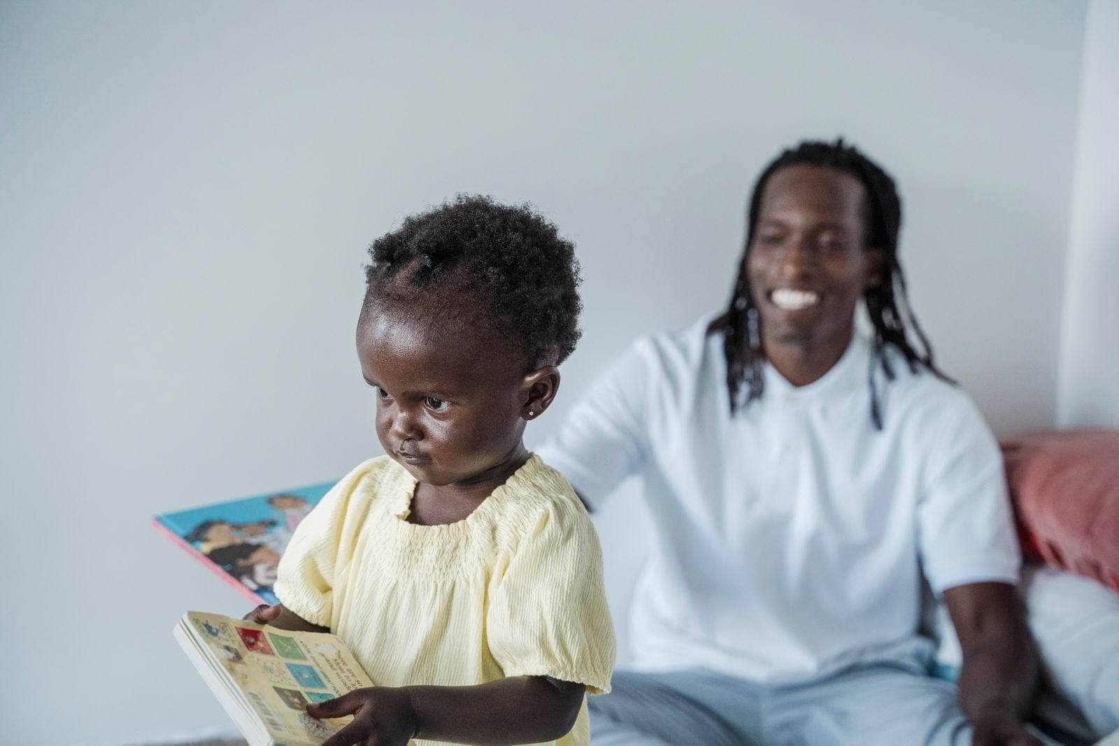 A young child holding a picture book beside an adult