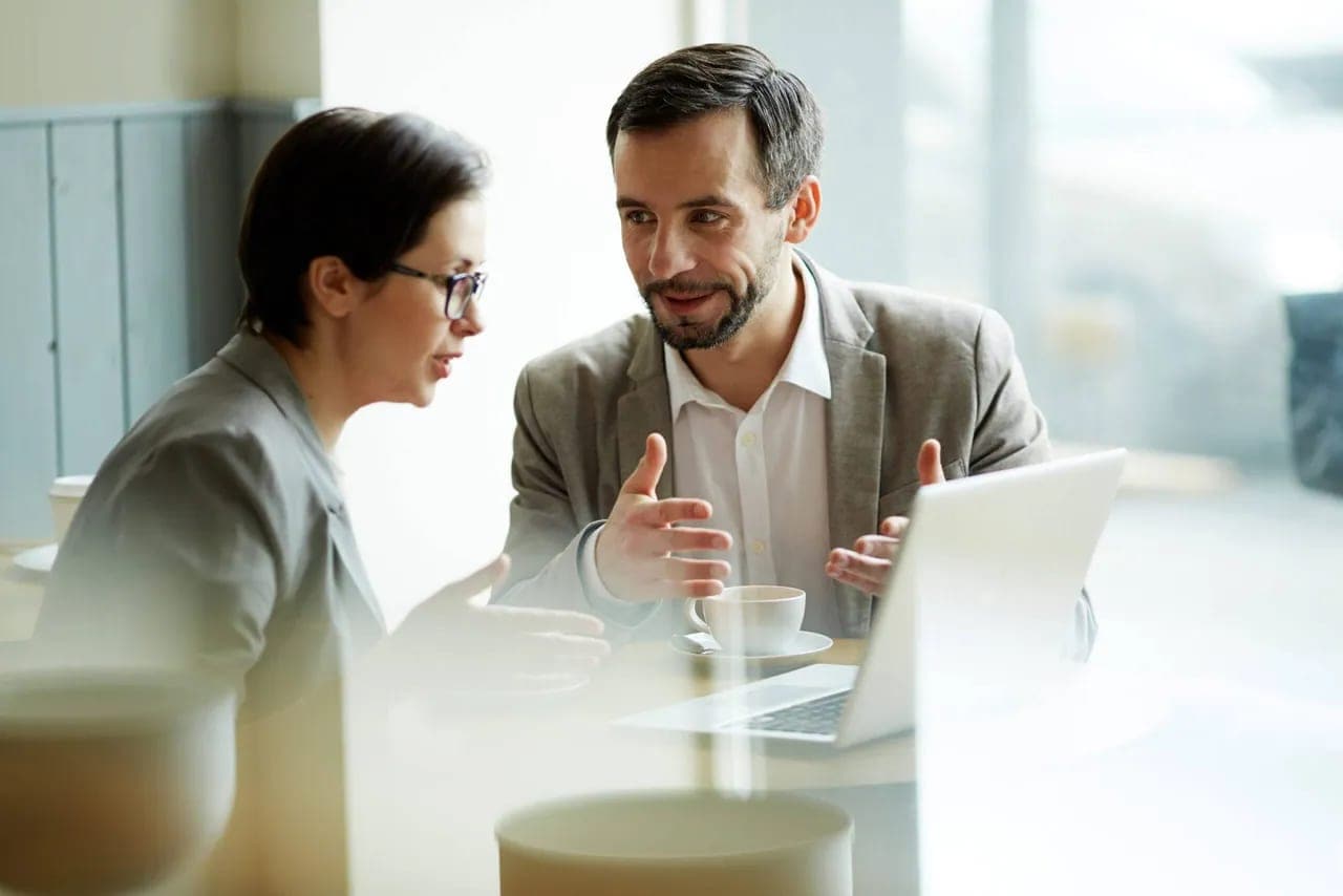 Two colleagues discussing a project beside a laptop