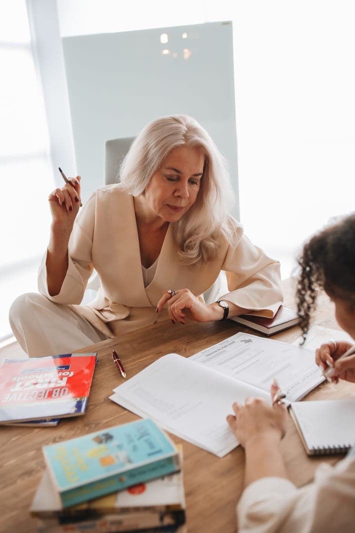 An instructor and student discussing an open textbook across a table