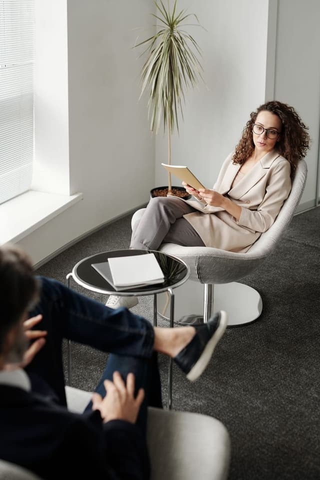 A woman holding a tablet while listening to a man seated opposite