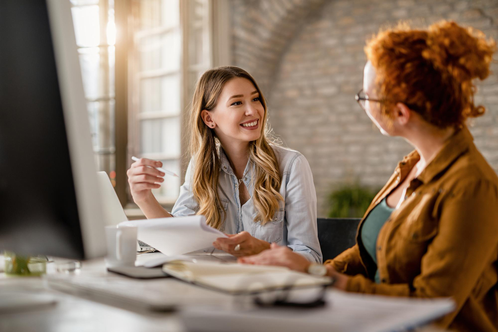 Two professionals in a one-on-one accent reduction coaching session, discussing communication goals at a desk