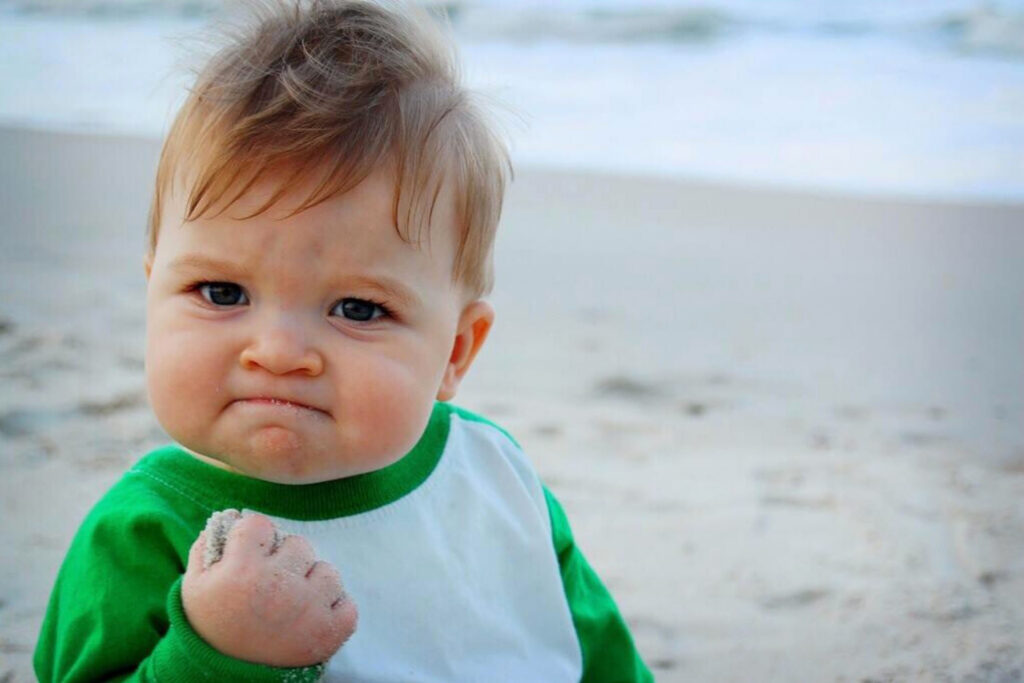 image of a kid on a beach making a fist in triumph.